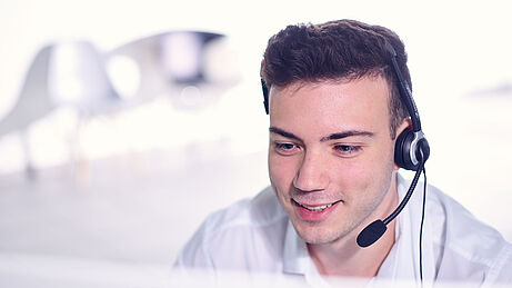 Support-Mitarbeiter von ibo mit Headset am Computer
